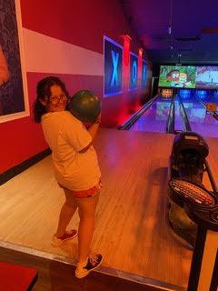 Student poses with bowling ball in front of alley
