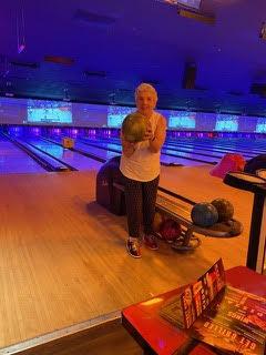 Counselor stands with bowling ball in front of lanes