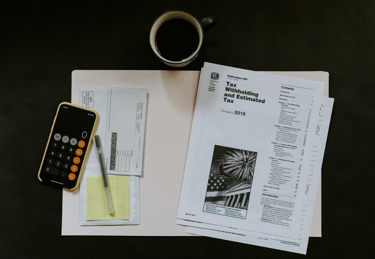 collection of tax papers, a cup of coffee, and the calculator app on a smartphone