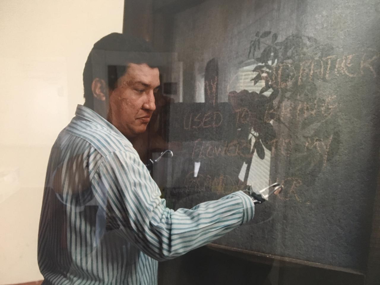 Man with prosthetic hands writing on chalkboard