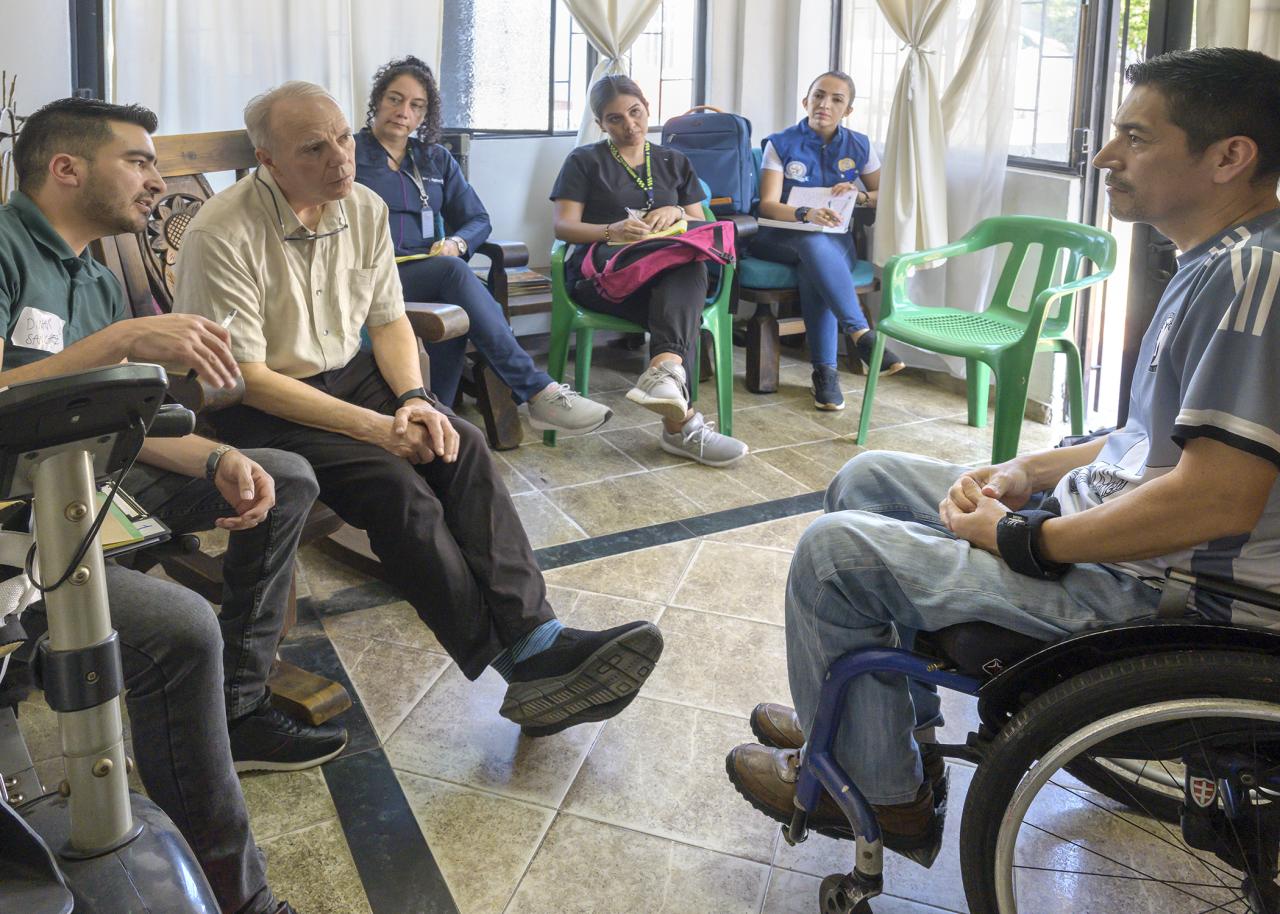 Five people interviewing a man in a wheelchair