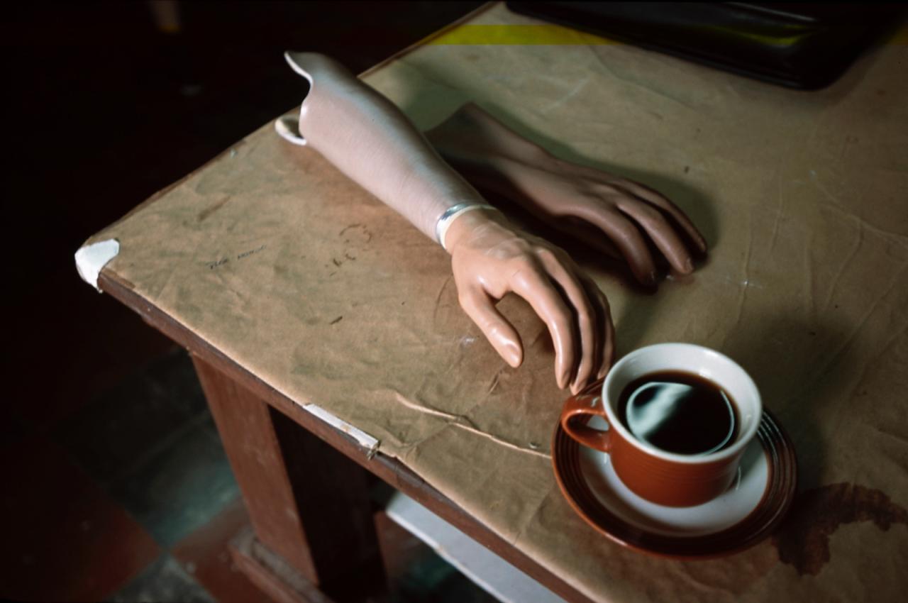 Prosthetic arm laying on table next to a cup of coffee (photo by Stephen Petegorsky)
