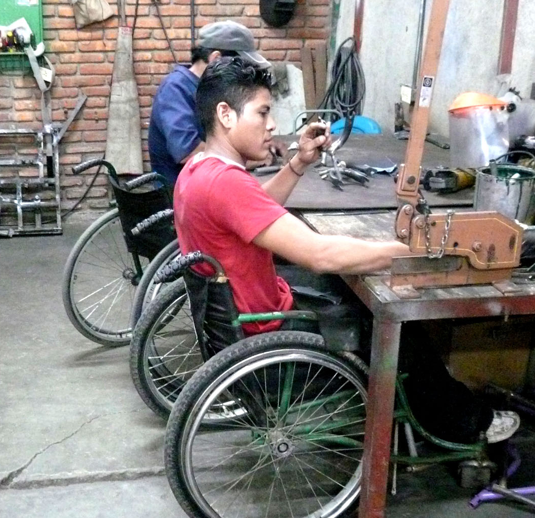 two men in wheelchairs building mobility devices (photo by Stephen Petegorsky)