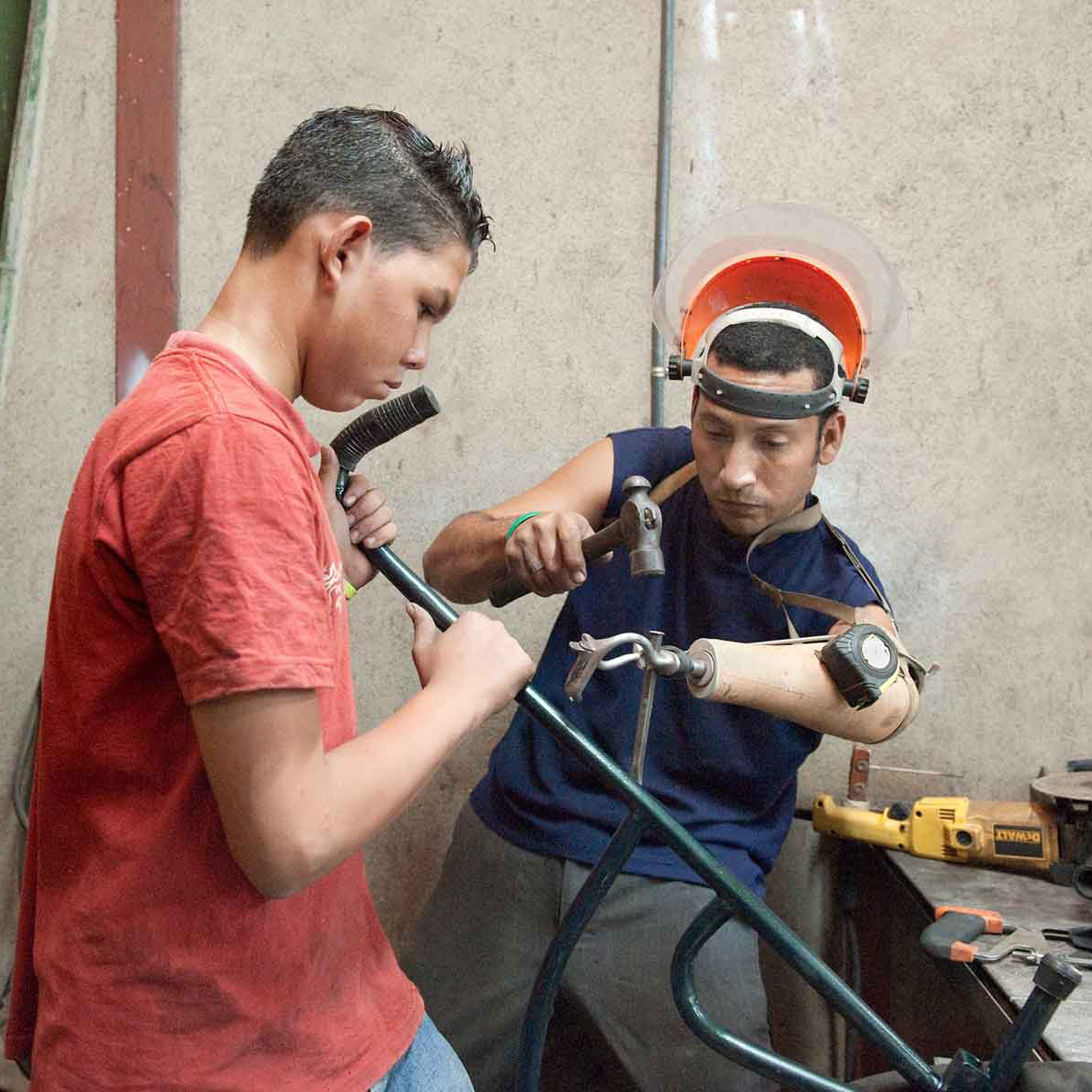 Two men with prosthetics in workshop building a wheelchair (photo by Stephen Petegorsky)