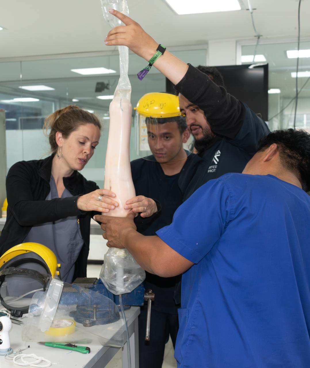 Polus Center Board President and Certified Prosthetist, Nellie Zarif, building an artificial leg in Colombian prosthetic clinic with two other technicians in Colombia.