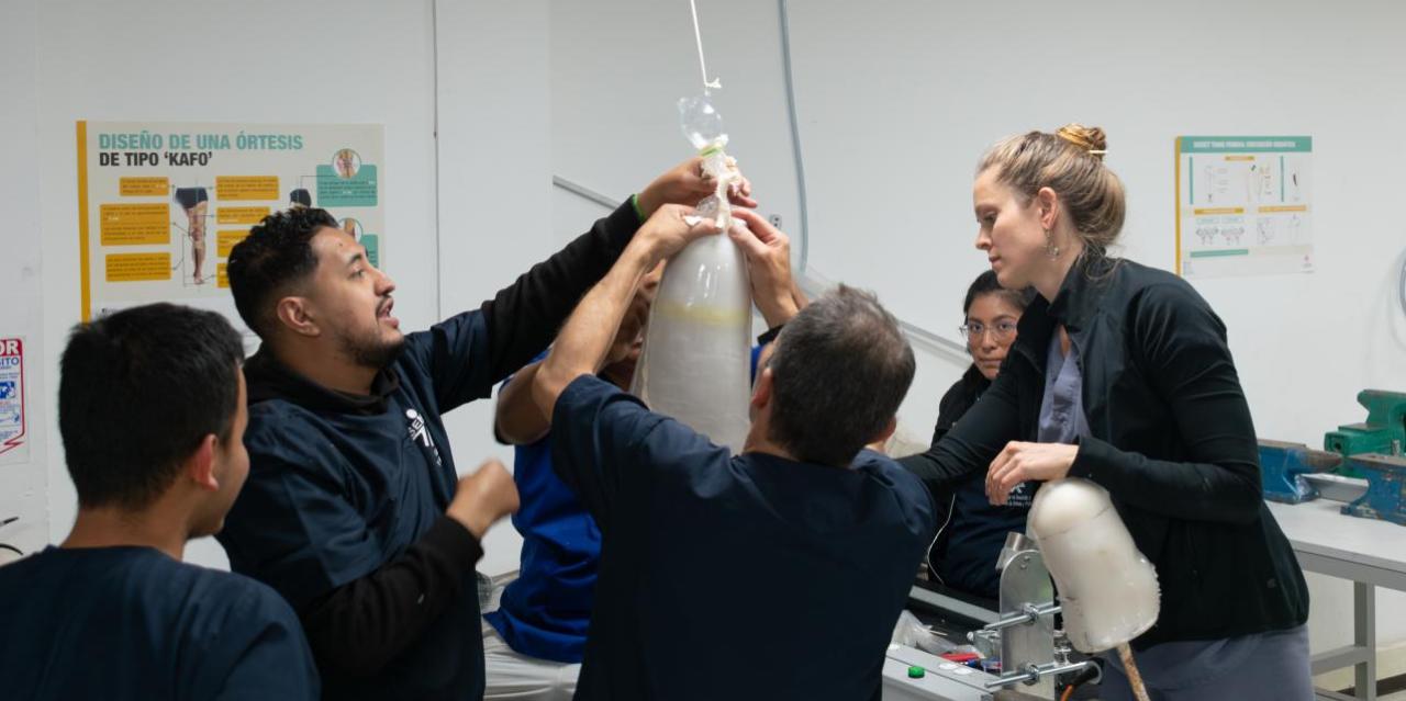 Polus Center Board President and Certified Prosthetist, Nellie Zarif, with prosthetic technician trainees building an artificial leg in Colombian prosthetic clinic. 