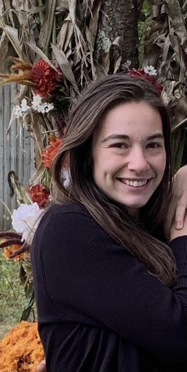 Headshot of Alyse by a tree with flowers