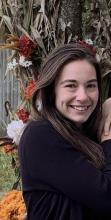 Headshot of Alyse by a tree with flowers