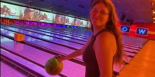 Student holds a bowling ball by bowling lanes