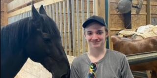 A student stands beside a horse in the stables